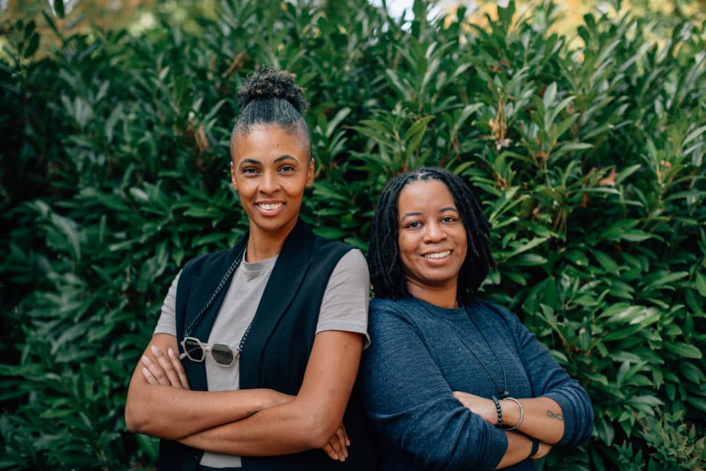 two black woman co-founders standing shoulder to shoulder smiling with arms crossed